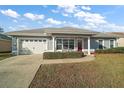 Gray house with white garage door and red front door, landscaped lawn at 11579 Se 172Nd Loop, Summerfield, FL 34491