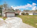 Inviting front yard view of this one-story home, showcasing the driveway, garage, and green space at 11744 Oswalt Rd, Clermont, FL 34711