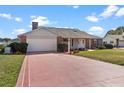 Well-maintained home featuring an attached garage, brick facade, manicured lawn, and inviting front entrance at 1320 Cove Pl, Tavares, FL 32778