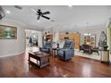 Inviting living room featuring hardwood floors, comfortable seating, and an open layout to the kitchen and dining area at 13914 Se 96Th Cir, Summerfield, FL 34491