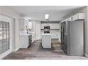 Well-lit kitchen with a kitchen island, stainless steel refrigerator, and modern white cabinets at 1617 Myrtle Lake Ave, Fruitland Park, FL 34731