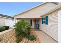 Front entry of tan house with teal shutters and door at 2222 Southwood Dr, The Villages, FL 32162