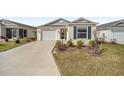 Single Gathering house featuring a two-car garage, screen front door, and well-kept landscaping at 7260 Draper Ave, The Villages, FL 34762