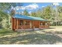 Cozy log cabin with a green metal roof and a classic covered front porch at 775 Abeble Rd, Lady Lake, FL 32159