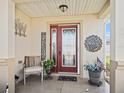 Welcoming front porch featuring decorative door with a welcome sign, chair, and potted plants at 8662 Se 133Rd Ln, Summerfield, FL 34491