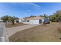 A well-maintained single-story home featuring a neatly landscaped lawn and a two-car garage, enhanced by a clear blue sky at 9951 Se 175Th St, Summerfield, FL 34491