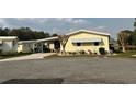 Charming yellow mobile home featuring a covered carport, well-maintained landscaping, and a peaceful neighborhood setting at 122 Tamarisk Way, Leesburg, FL 34748