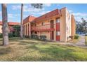Exterior view of a two-story condo building featuring red roofing and balconies overlooking lush landscaping at 2804 N Powers Dr # 27, Orlando, FL 32818