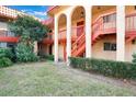 Exterior view of a two-story condo building with red stairs and balconies, framed by mature trees at 2804 N Powers Dr # 27, Orlando, FL 32818