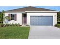 Home exterior featuring well-kept lawn, two-car garage, and colorful front door and window shutters at 2932 Supermarine Rd, Tavares, FL 32778