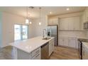Bright kitchen with white cabinets, stainless steel appliances, and island with sink at 2932 Supermarine Rd, Tavares, FL 32778