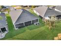 Overhead view of a screened-in back patio, a lush lawn and garden, and the dark roof of a charming single-story home at 5819 White Ibis, The Villages, FL 32163