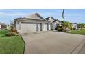 A wide driveway leads to a well maintained home, complemented by tropical landscaping, and two-car garage at 5819 White Ibis, The Villages, FL 32163