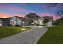 Charming light blue home featuring a circular paved driveway, well-manicured lawn, and mature landscaping at 1001 Del Rio Dr, The Villages, FL 32159