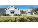 Charming light blue home featuring a paved driveway, well-manicured lawn, and mature landscaping at 1001 Del Rio Dr, The Villages, FL 32159