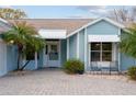 Close up of front of light blue house, shows front entry, paved driveway, and mature landscaping at 1001 Del Rio Dr, The Villages, FL 32159