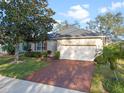 Inviting home with a brick driveway, two-car garage, and lush landscaping at 1067 Mesa Verde Court, Clermont, FL 34711