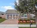 Charming home with a two-car garage, stone accents, complemented by brick pavers and lovely landscaping at 123 Bayou Bend Rd, Groveland, FL 34736