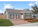 Charming home featuring a two-car garage, stone accents, complemented by brick pavers and colorful landscaping at 123 Bayou Bend Rd, Groveland, FL 34736