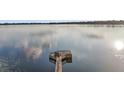 Scenic view of a private wooden dock on a serene, glassy lake reflecting the sky and clouds at 19215 Park Place Blvd, Eustis, FL 32736