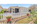 Quaint home exterior featuring a cozy patio, white picket fence, and decorative landscaping at 308 Emmalee Pl, The Villages, FL 32162