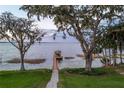 Peaceful view of the lake and boat dock framed by mature trees and manicured lawn at 415 Carman Dr, Leesburg, FL 34748