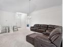 Bright living room with neutral carpet, featuring an elegant light fixture, and glass dining table at 464 Dominish Estates Dr, Apopka, FL 32712