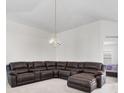 Spacious living room featuring neutral carpet, a modern chandelier, and a comfortable large couch at 464 Dominish Estates Dr, Apopka, FL 32712