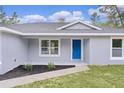 Inviting front porch with blue door, new landscaping, and neutral gray paint at 68 Malauka Pass Crse, Ocklawaha, FL 32179