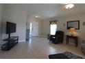 Open living room with neutral tile flooring, comfortable seating, and a view of the front entryway at 8660 Se 132Nd Ln, Summerfield, FL 34491