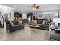 A spacious living room featuring tile flooring, comfortable seating, and an open layout to the kitchen at 887 Daisy Hill Ct, Apopka, FL 32712