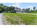 A home's backyard featuring a three-car garage, a shed, and sprawling green lawn at 9905 Skylark Ln, Groveland, FL 34736