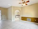 A cozy living room with tile floors, ceiling fan and an archway leading into the kitchen at 100 Grand Reserve Dr, Davenport, FL 33837