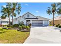 Charming one-story home with a three-car garage and a well-manicured lawn at 1044 Alcove Loop, The Villages, FL 32162