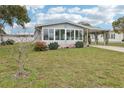 Inviting home featuring enclosed porch area with many windows, carport, lawn and concrete drive at 1430 Mohawk Cir, Tavares, FL 32778