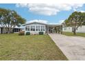 Charming single-story home with a spacious lawn, enclosed sunroom, and convenient carport at 1430 Mohawk Cir, Tavares, FL 32778