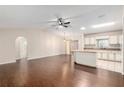 Open-concept living room with elegant wood flooring, ceiling fan and seamless flow into the bright kitchen at 17764 Se 95Th Ct, Summerfield, FL 34491