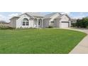 Well-manicured front lawn with a white stucco home and attached two car garage at 17899 Se 115Th Cir, Summerfield, FL 34491