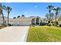 Charming home featuring a well-manicured lawn, three-car garage, and inviting front entrance at 1840 Madero Dr, The Villages, FL 32159