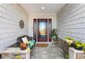 Cozy front porch with seating, stylish stone accents, and a welcoming entrance door at 1914 Antonia Pl, The Villages, FL 32159