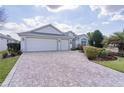 A three car garage home with a brick paver driveway and manicured lawn at 2022 Abordale Ln, The Villages, FL 32162