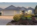 Beautiful home at dusk featuring a brick driveway and lush, mature landscaping at 2022 Abordale Ln, The Villages, FL 32162