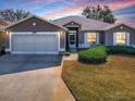 Charming home featuring a two-car garage, and inviting front garden with lush green shrubs at 320 Bentwood Dr, Leesburg, FL 34748