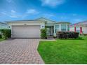 Well-kept one-story home with attached two-car garage, brick driveway and lush green lawn at 32708 Westwood Loop, Leesburg, FL 34748