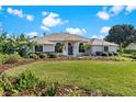 Charming home with lush green lawn, beautiful landscaping, and welcoming blue front door under a sunny sky at 39136 Harbor Hills Blvd, Lady Lake, FL 32159