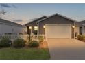 Charming single-story home with a white picket fence and well-maintained landscaping at dusk at 5597 Gracie Ln, The Villages, FL 32163