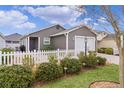 Single-story home featuring a white picket fence, neat landscaping and a gray exterior at 5597 Gracie Ln, The Villages, FL 32163