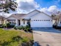 Charming single-story home with white siding, well-manicured lawn, and a two car garage at 610 Mallory Hill Dr, The Villages, FL 32162