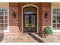 Elegant arched doorway featuring double doors with decorative glass, flanked by sidelights and sconce lighting at 631 Old Mount Dora Rd, Eustis, FL 32726