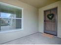 Cozy covered front porch featuring neutral paint and a charming wreath hanging on the front door at 796 Elliott Ave, The Villages, FL 32163